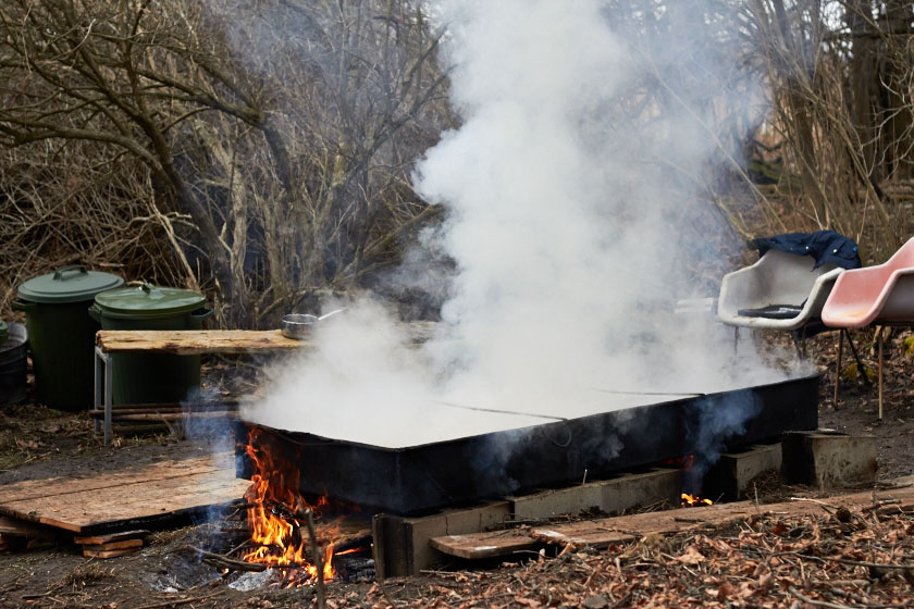 Boiling the sap in open vats outdoors. The maple syrup is almost ready. 